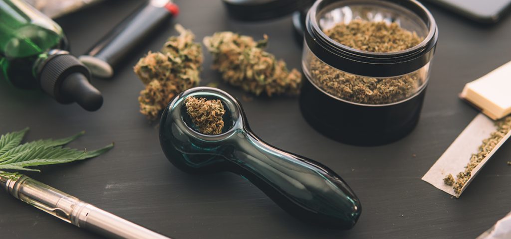 Marijuana smoking pipe CBD and THC on buds in cannabis. Macro Cannabis buds weed on black wood background. Cannabis legalisation.